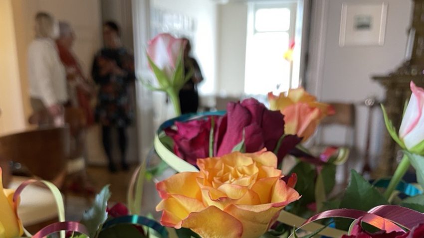 Seniorien vapputapaaminen. Kuvassa kukkakimppu aja taustalla Apollonian toimistoa ja vierailijoita.